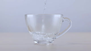 Fresh Water Pouring into a Clear Glass Cup on Wooden Table