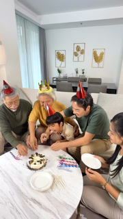 Multigenerational Asian Family Cutting Birthday Cake at Home