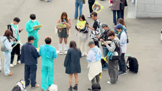 Young Fans Holding Concert Merchandise and Smartphones Outdoors in Tokyo