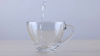 Pouring Fresh Water into a Clear Glass Cup on Wooden Table