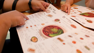 People Pointing at Menu Choosing Food in Restaurant