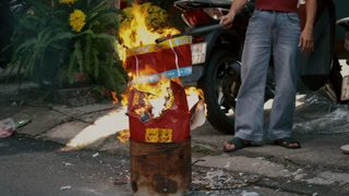 Burning joss paper in metal barrel during street ritual