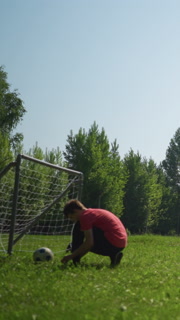 A grandfather and grandson play football, the grandfather throws, the grandson heads the ball, nearby, someone ties his shoelace near a