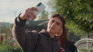 white teen couple kissing during selfie, intimate embrace and phone closeup under warm sunset light in city garden influencerstyle pose