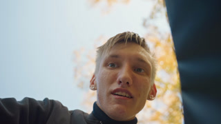 looking into delivery bag white male, courier inspecting grocery package under autumn tree, low camera angle, hands reaching inside bag