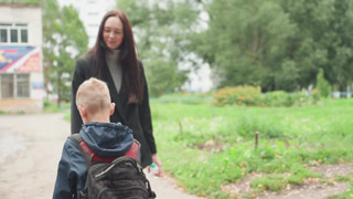 Caregiver calms youngster. Adult assures anxious young boy. Mother comforts son facing first school day. Respective guardian offers comfort