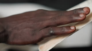 Black man hands flipping poetry pages, closeup, gentle turning, preparing reading for date night, soft studio light, textured paper, focused