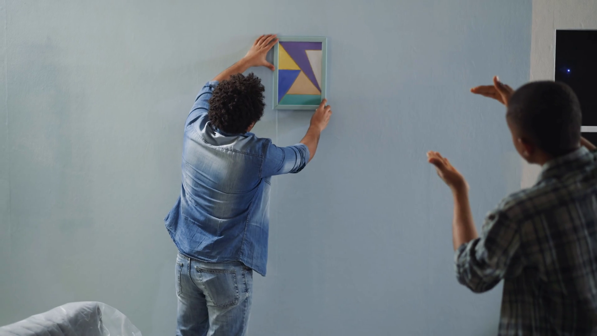 Black Man Helps Colleague To Hang Drawing Stock Footage SBV347308567