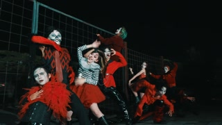 Energetic Horror Clown Dance Crew Posing by Fence at Night