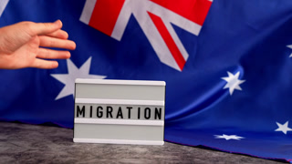 Message MIGRATION on background of Australian flag made from silk. Australia national flag with concept of tourism and traveling. welcoming