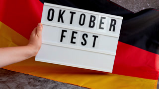 Lightbox with text OKTOBERFEST National symbol of Germany. German wave silky flag background. Concept of traditional beer Bavarian festival