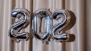 Stop motion Happy new year 2024 metallic balloons on atlas textile background. Greeting card silver foil balloons numbers Christmas holiday