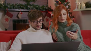 Young couple makes online purchase through Internet store using laptop, buy Christmas presents doing online ecommerce shopping purchase payment. Christmas Gifts purchase online concept.