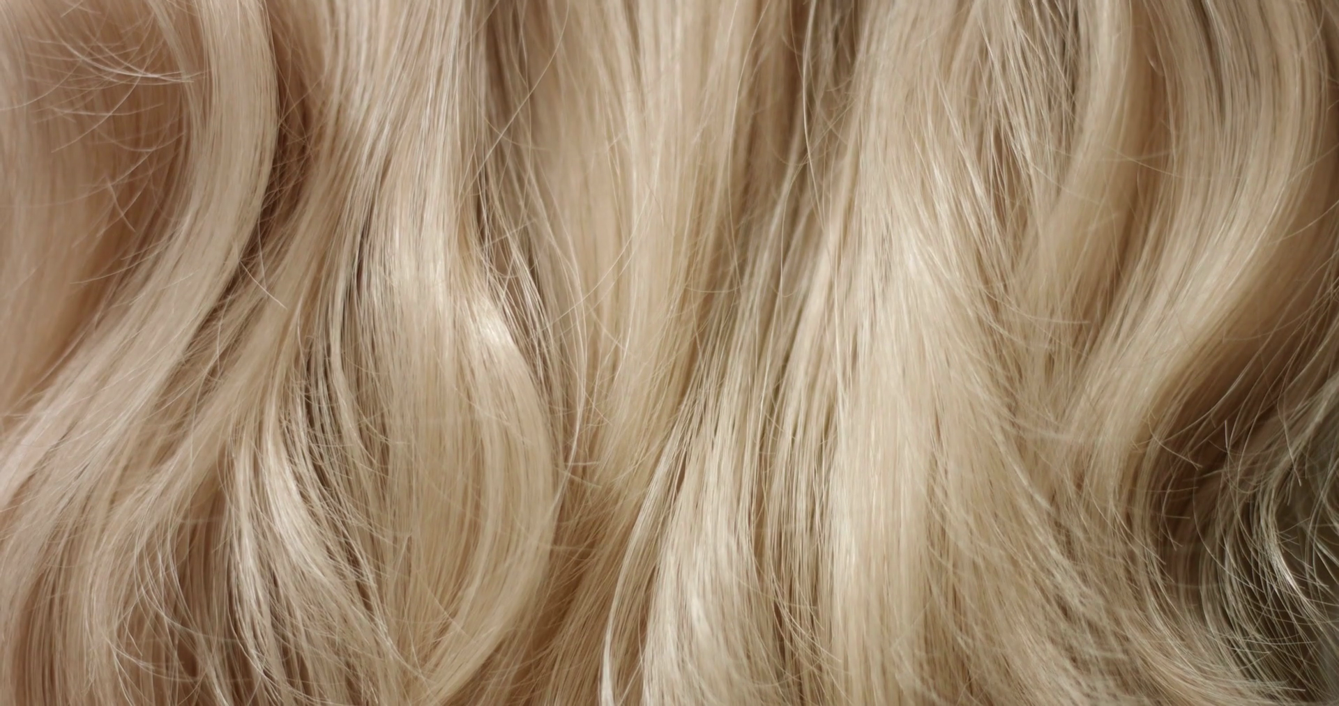 Close up shot of brushing long wavy woman's blond hair with a hairbrush