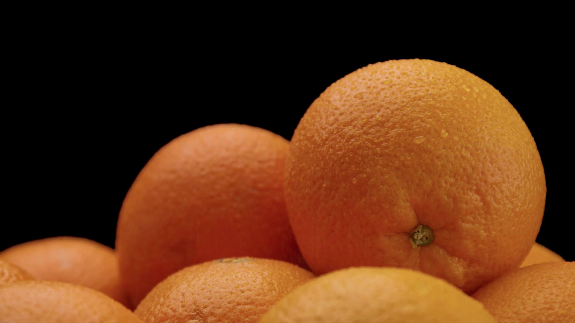 closeup of oranges on black background. Fresh with drops of water on