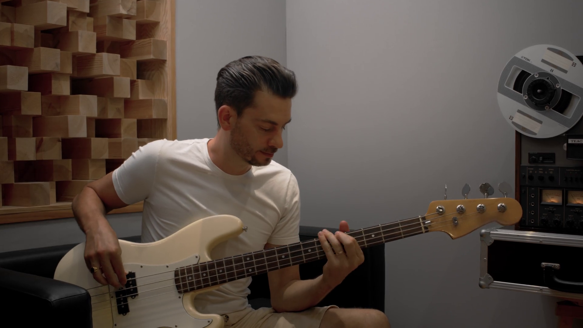 man playing bass guitar in sound studio with retro audio tape recorder at background Stock Video