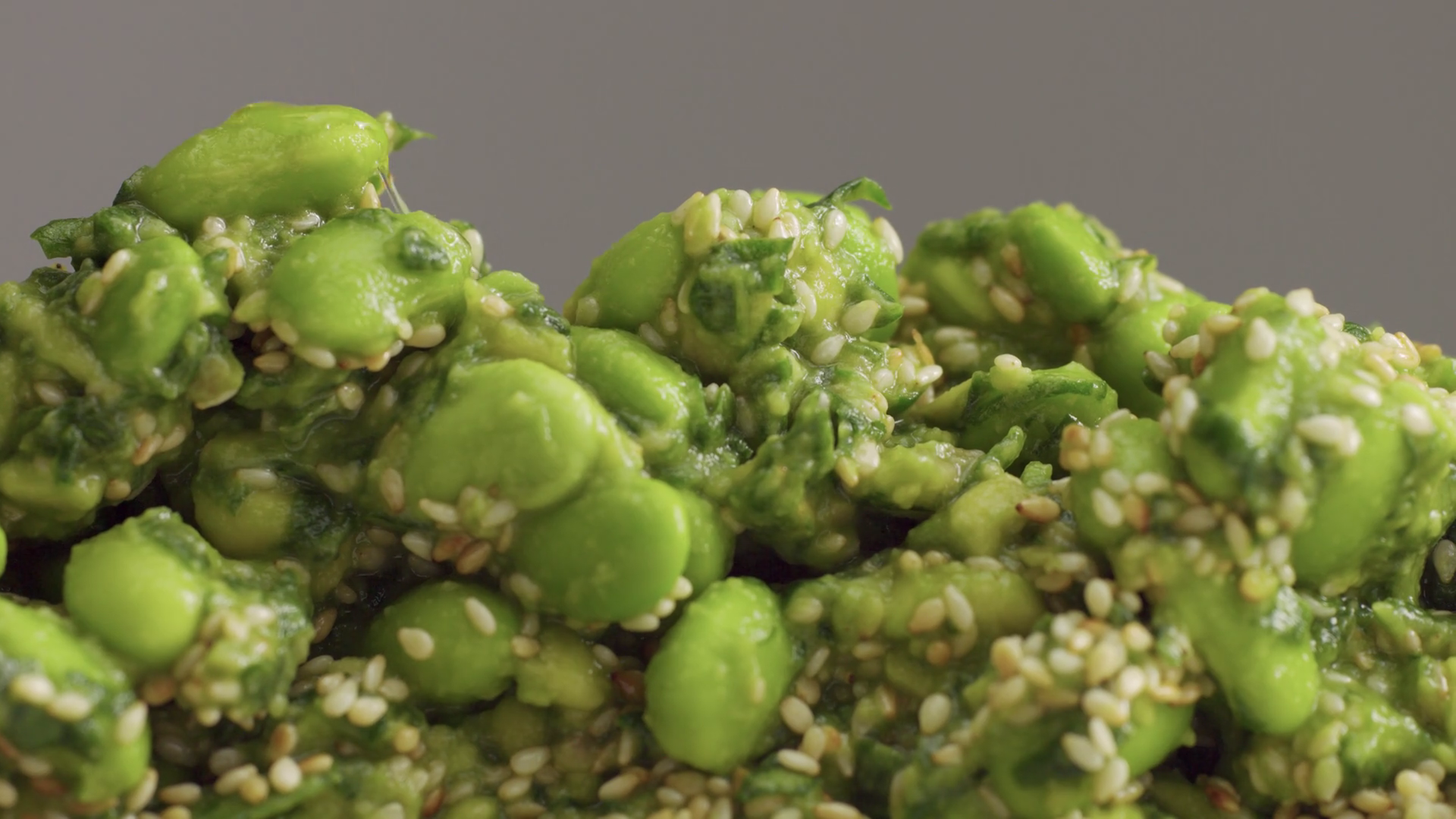 mix of edamame with sesame seeds and avocado and olive oil pouring on it. Green veggie food