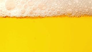 Close up of refreshing beer with frothy foam and golden liquid in bright light