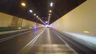 Driving through a long tunnel with bright lights at the end of the road ahead