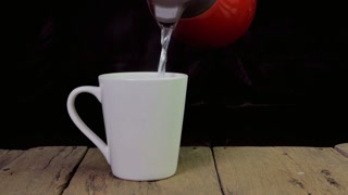 Hot water being poured into a white mug on a rustic wooden table background shot