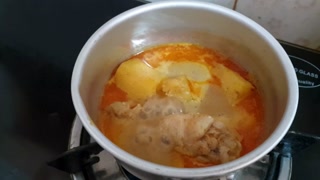 Chicken curry with potatoes simmering in a pot on a stove top for a meal prep