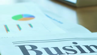 Business newspaper headline with charts and calculator on a desk in soft light