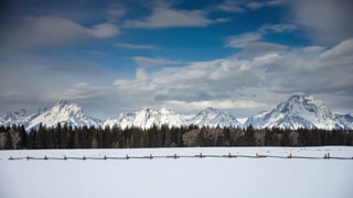 Grand teton mountain range in wyoming with snow and a cloudy blue sky