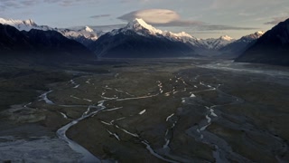 Aerial shot of beautiful mountains above a valley with rivers running through during sunrise, rising shot. Mt Cook, New Zealand.