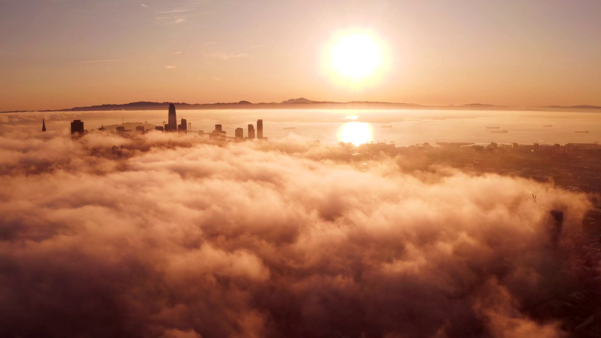 Flying over the clouds during morning sunrise in San Francisco with