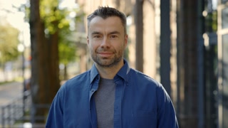 Portrait of the man standing in the street wearing casual clothes smiling looking at the camera. Businessman standing near office district
