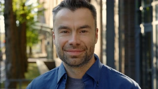Portrait of the man standing in the street wearing casual clothes smiling looking at the camera. Confident businessman standing smiling and