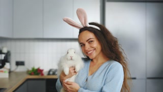 Portrait of the Young Woman Holding The Fluffy Easter Rabbit, Wearing Bunny Ears. Smiling Lady Is Getting Ready For The Spring Holiday