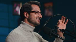 Portrait of man host in turtleneck sweater talks in mic on podcast in studio