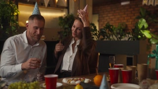 A happy girl in a business suit puts a festive cap on her head during a holiday and corporate event with her colleagues in the office