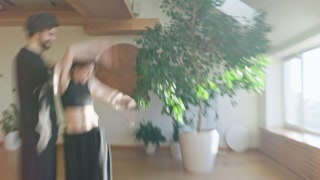 Two dancers in black spin in a blurred motion in a cozy studio with plants and soft daylight showing artistic energy intimacy and expressive