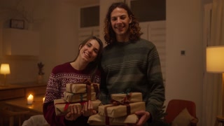 Couple celebrating Christmas with wrapped gifts in cozy room by the tree