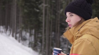 Woman with Coffee Cup in Ski Resort, Walking on Snow. Young Woman in Knitted Hat.