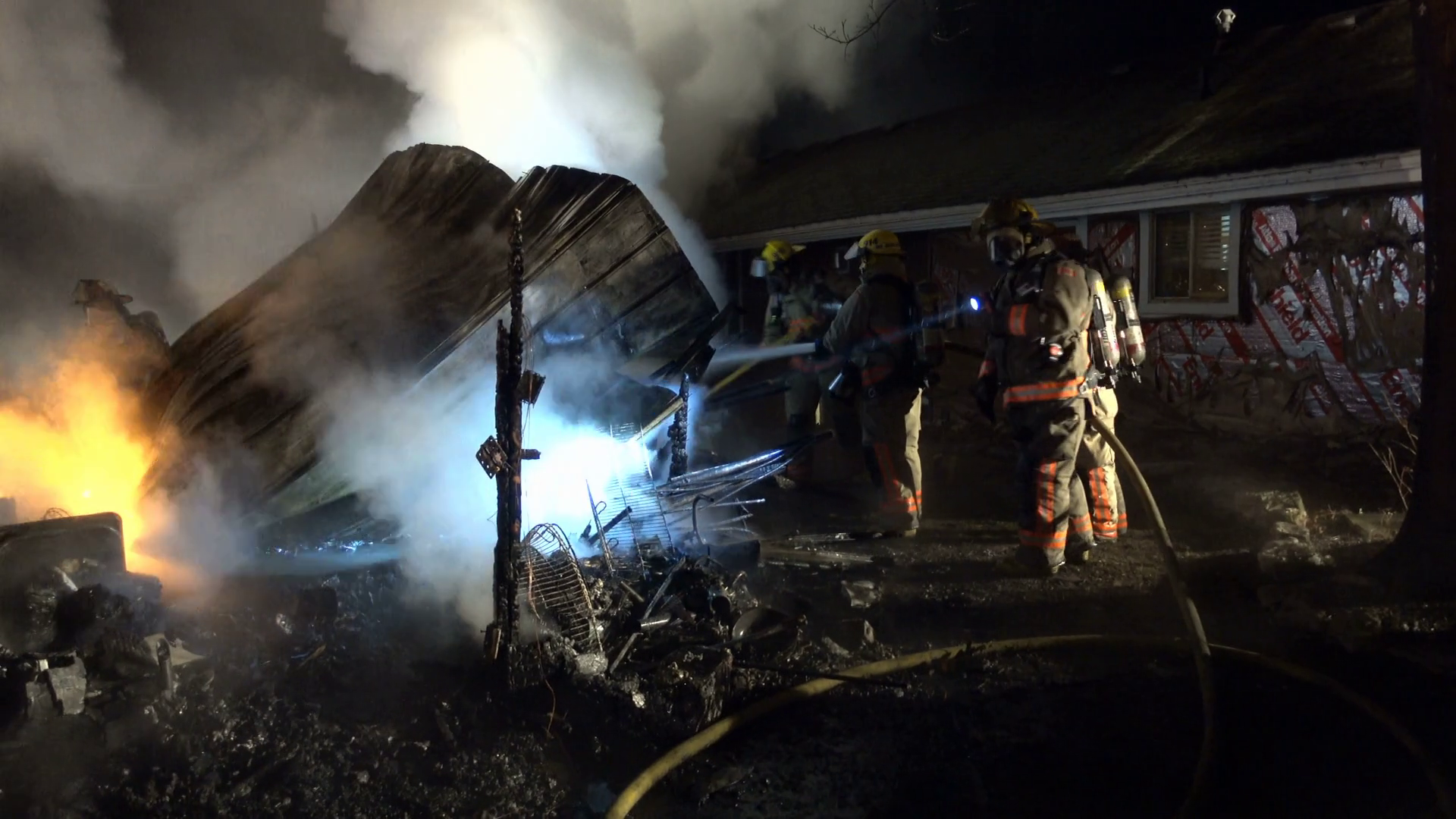 Panning of firemen sifting through ruins of an active house fire at