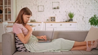Woman using computer on couch in living room apartment