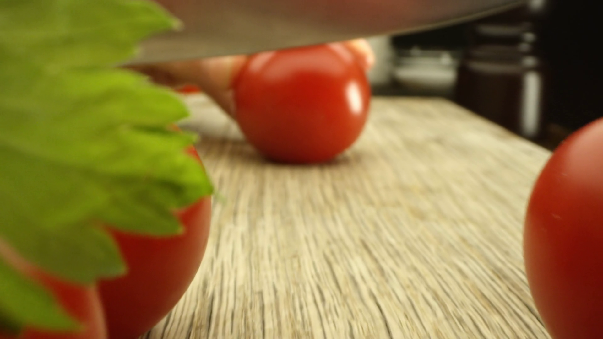 Cutting a fresh tomato with a knife on a table with herbs. Stock Video