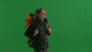 A Walking Male Tourist with a Hiking Backpack on His Back Stops and Waves His Hand in Greeting When. A walking male tourist with a hiking backpack on his back, stops and waves his hand in greeting when he sees his acquaintances. A man hiker in the st