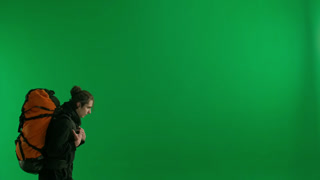 A Male Traveler Takes Pictures with a Camera While Hiking A Tourist with a Backpack on His Back. A male traveler takes pictures with a camera while hiking. A tourist with a backpack on his back stands in a studio on a green screen close up. Concept o
