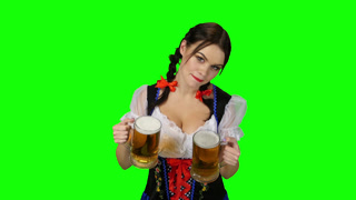 Girl in Bavarian Costume Offers a Glass of Beer. Green Screen. Girl with pigtails on the head dancing in a festive costume at oktoberfeste with glass on pickup and proposes to drink beer. Green screen