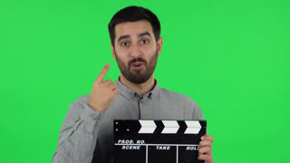 Portrait of Brunette Guy Is Holding a Movie in His Hands. Green Screen