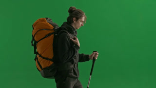 Side View of a Hiker with a Trekking Sticks Close Up A Man with a Backpack on His Back is Walking in. Side view of a hiker with a trekking sticks close up. A man with a backpack on his back is walking in the studio on a green screen. The concept of h