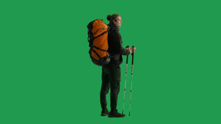 A Male Tourist with a Backpack on His Back Walks in the Studio on a Green Screen Close Up Side View. A male tourist with a backpack on his back walks in the studio on a green screen close up. Side view. Hiking trek rest travel trip concept
