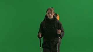 Side View of a Traveler with Backpack and Trekking Poles in His Hands The Man Looks Around with a. Side view of a traveler with hiking backpack on his back and trekking poles in his hands. The man looks around with a smile and wipes sweat from his fo