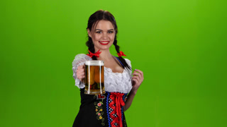 Woman in Bavarian Costume Dances with a Glass of Beer in the Pickup. Green Screen. Girl with pigtails on the head dancing in a festive in costume at oktoberfeste with glass on pickup and proposes to drink beer. Green screen