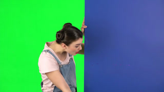 Portrait of Attractive Office Girl on Chroma Key Green Screen Woman in Skirt and Blouse Peeking, A woman with red hair in a white shirt and black skirt peeks out from behind a tall green partition on a green screen background. She looks to her left w
