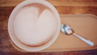 Top down view of a cappuccino with creamy milk foam served on a wooden table